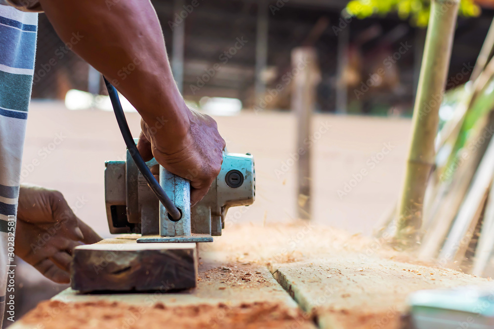 The carpenter's hands use a planer on the floor and create dust from work. The carpenter's hands use a planer on the floor and create dust from work.