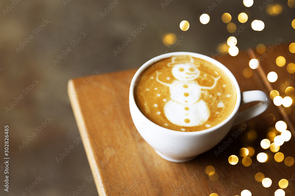 Fototapeta Tasty cappuccino with Christmas snowman art with some blurred lights.