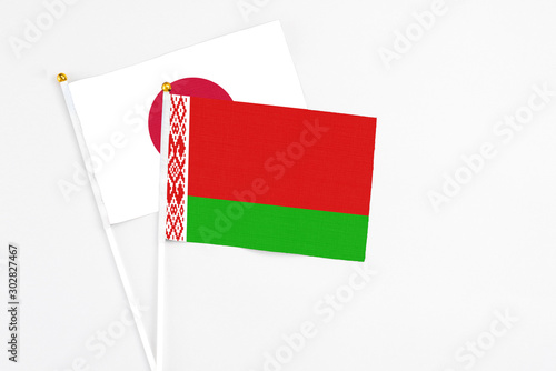 Belarus and Japan stick flags on white background. High quality fabric, miniature national flag. Peaceful global concept.White floor for copy space. photo