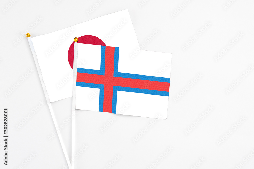 Faroe Islands and Japan stick flags on white background. High quality fabric, miniature national flag. Peaceful global concept.White floor for copy space. Faroe Islands and Japan stick flags on white background. High quality fabric, miniature national flag. Peaceful global concept.White floor for copy space.