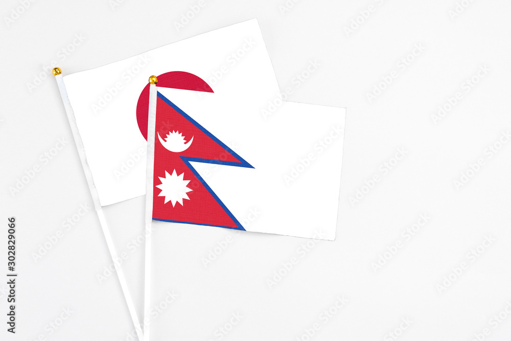 Obraz premium Nepal and Japan stick flags on white background. High quality fabric, miniature national flag. Peaceful global concept.White floor for copy space.