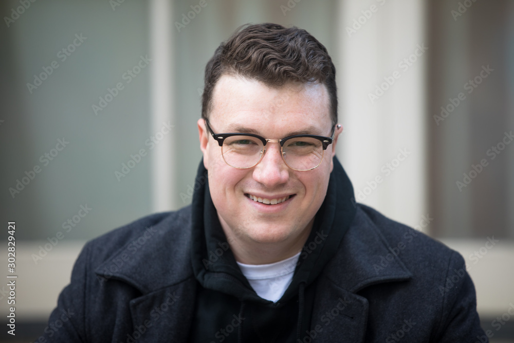 A caucasian male wearing a black hoodie sweater and glasses poses in a garden while surrounded by fall foliage on a cold afternoon. A caucasian male wearing a black hoodie sweater and glasses poses in a garden while surrounded by fall foliage on a cold afternoon.