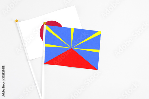 Reunion and Japan stick flags on white background. High quality fabric, miniature national flag. Peaceful global concept.White floor for copy space.