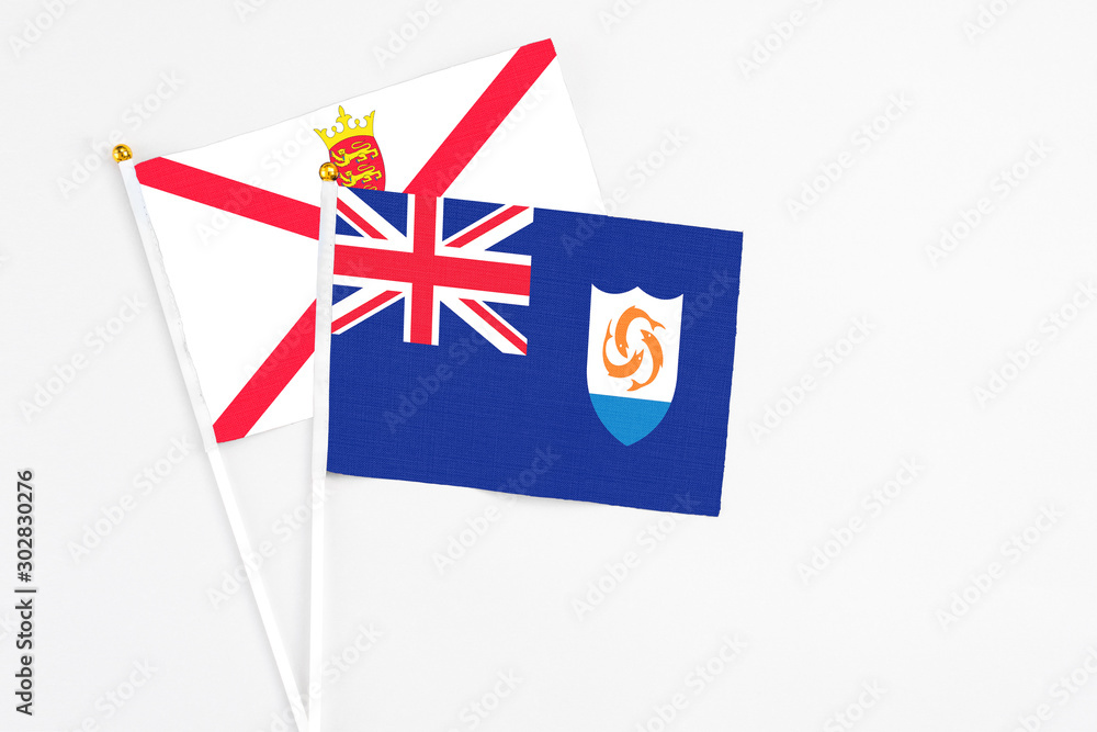 Fototapeta premium Anguilla and Jersey stick flags on white background. High quality fabric, miniature national flag. Peaceful global concept.White floor for copy space.