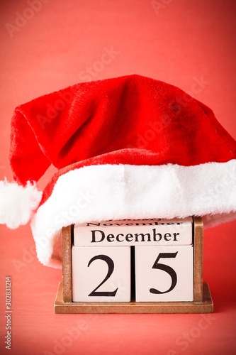 Christmas concept: 25th December wooden calendar with Christmas decorations on a red background, copy space for text