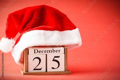 Christmas concept: 25th December wooden calendar with Christmas decorations on a red background, copy space for text