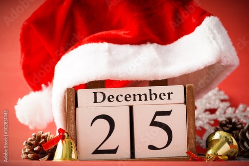 Christmas concept: 25th December wooden calendar with Christmas decorations on a red background, copy space for text