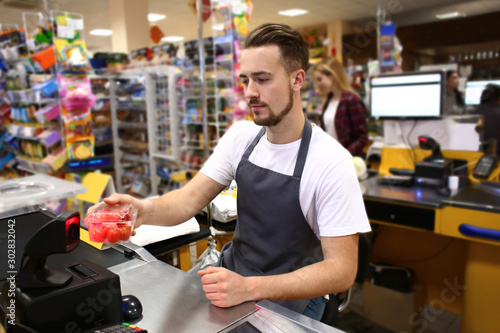 Male cashier checking out goods in supermarket photo