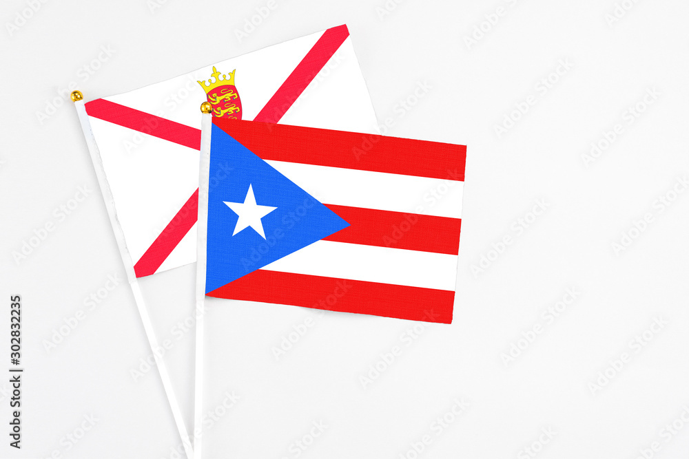 Obraz premium Puerto Rico and Jersey stick flags on white background. High quality fabric, miniature national flag. Peaceful global concept.White floor for copy space.