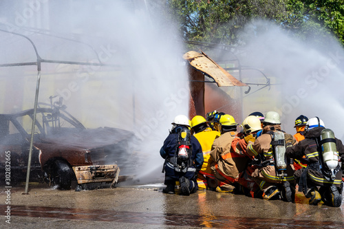 Brave firefighter using extinguisher and water from hose for fire fighting, Firefighter spraying high pressure water to fire, Firefighters fighting fire during training.