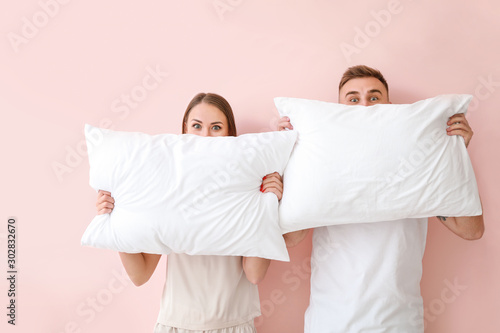 Young couple with pillows on color background photo