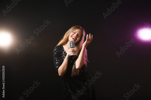 Beautiful young female singer with microphone on stage