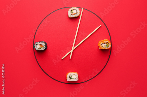 Creative clock made of tasty sushi and chopsticks on color background