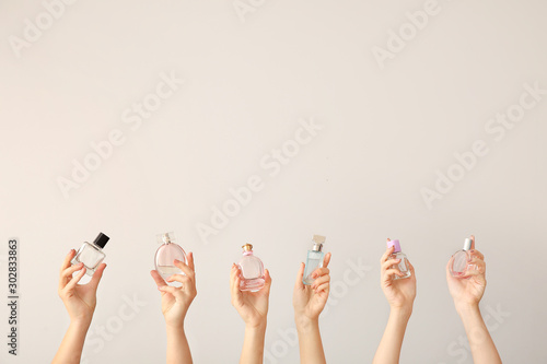 Female hands with different perfume bottles on grey background photo