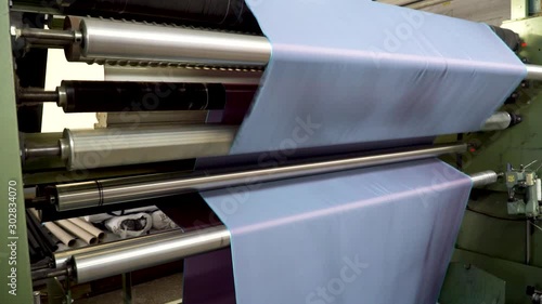 At a textile factory, checks the fabric roll on an automatic inspection machine. Examination of fabric for inspection and analysis before use for sewing clothes. 4k footage.
