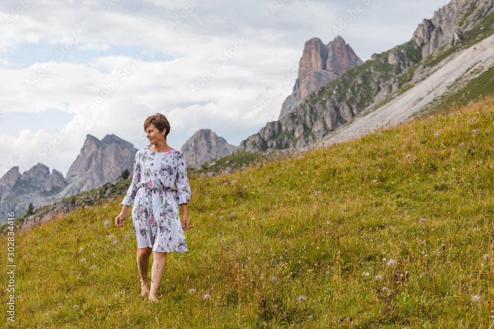 Girl in a dress on a background of mountains. Mountain valley of the Alps, Dolomites. Summer sunny day