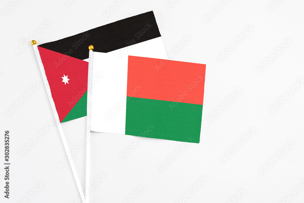 Madagascar and Jordan stick flags on white background. High quality fabric, miniature national flag. Peaceful global concept.White floor for copy space. Madagascar and Jordan stick flags on white background. High quality fabric, miniature national flag. Peaceful global concept.White floor for copy space.
