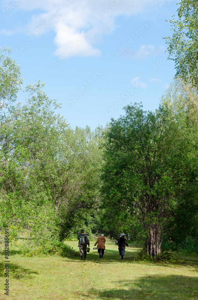 Yakut women and men walk on the green grass in the field of the Northern forest of Yakutia in the afternoon. Yakut women and men walk on the green grass in the field of the Northern forest of Yakutia in the afternoon.