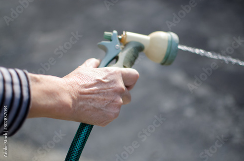 Hand of senior woman watering with water pistol