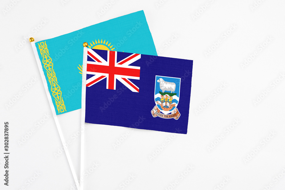 Fototapeta premium Falkland Islands and Kazakhstan stick flags on white background. High quality fabric, miniature national flag. Peaceful global concept.White floor for copy space.