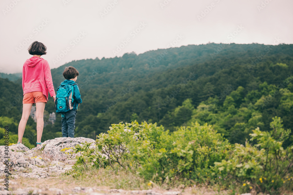 The boy with his mother on top of the mountain.
