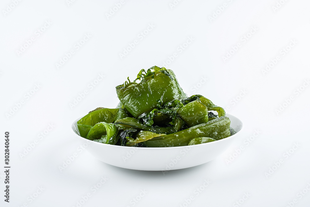 Fresh green salted sea cabbage stems on a saucer on a white background Fresh green salted sea cabbage stems on a saucer on a white background