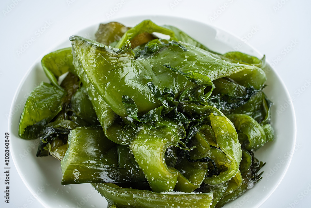 Fresh green salted sea cabbage stems on a saucer on a white background Fresh green salted sea cabbage stems on a saucer on a white background