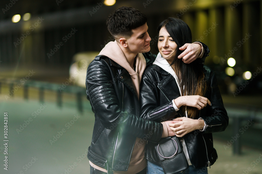 Fototapeta premium Young couple in love hug each other and have fun in underground crossing. Couple of man and woman walking into a tunnel. Happy to be together. Love, romantic, passion, tenderness concept.