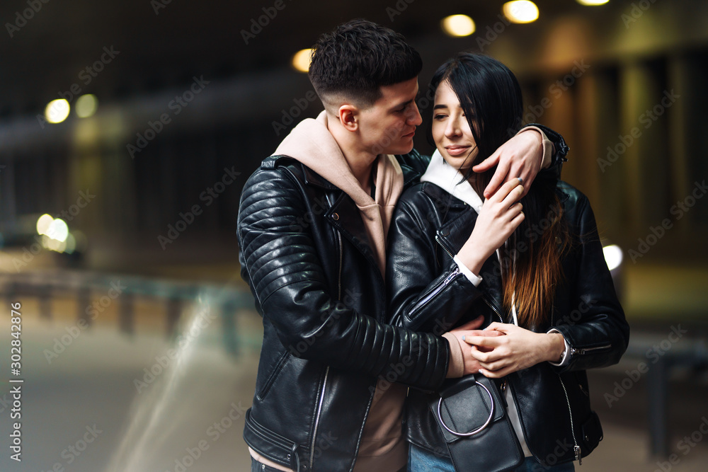 Young couple in love hug each other and have fun in underground crossing. Couple of man and woman walking into a tunnel. Happy to be together. Love, romantic, passion, tenderness concept. Young couple in love hug each other and have fun in underground crossing. Couple of man and woman walking into a tunnel. Happy to be together. Love, romantic, passion, tenderness concept.