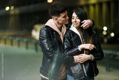Young couple in love hug each other and have fun in underground crossing. Couple of man and woman walking into a tunnel. Happy to be together. Love, romantic, passion, tenderness concept.