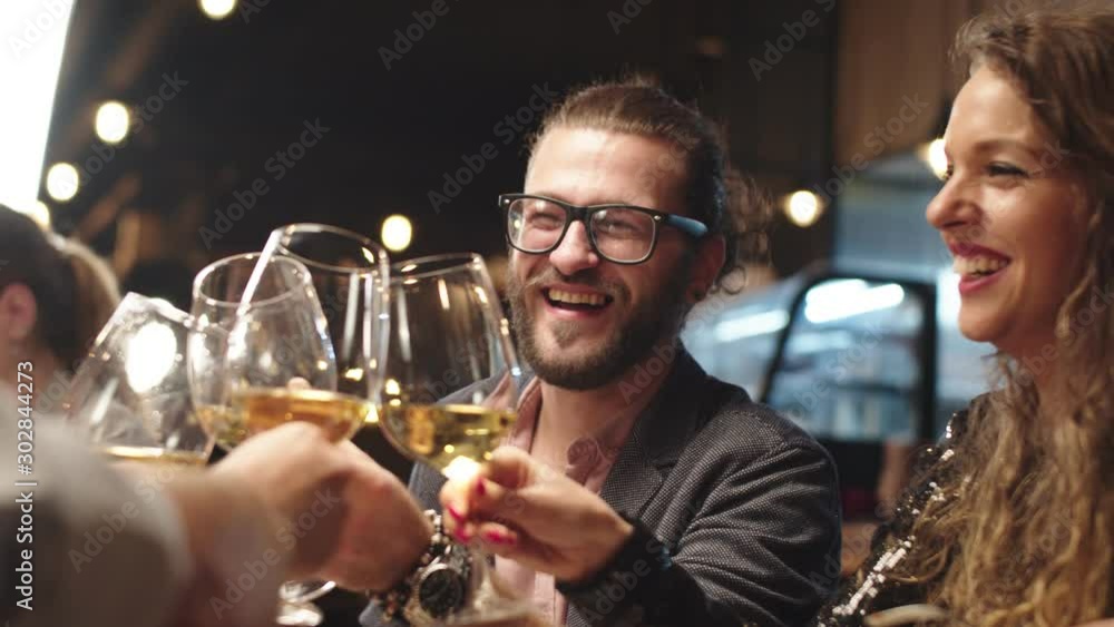Best friends sitting in restaurant for dinner and making a toast with white wine. On table is food. Best friends sitting in restaurant for dinner and making a toast with white wine. On table is food.