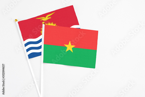 Burkina Faso and Kiribati stick flags on white background. High quality fabric, miniature national flag. Peaceful global concept.White floor for copy space.