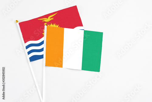 Cote D'Ivoire and Kiribati stick flags on white background. High quality fabric, miniature national flag. Peaceful global concept.White floor for copy space.