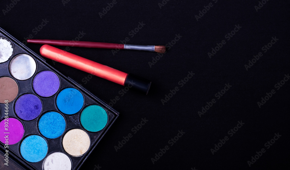 eyeshadow palette with brush and lipstick on black textured background eyeshadow palette with brush and lipstick on black textured background
