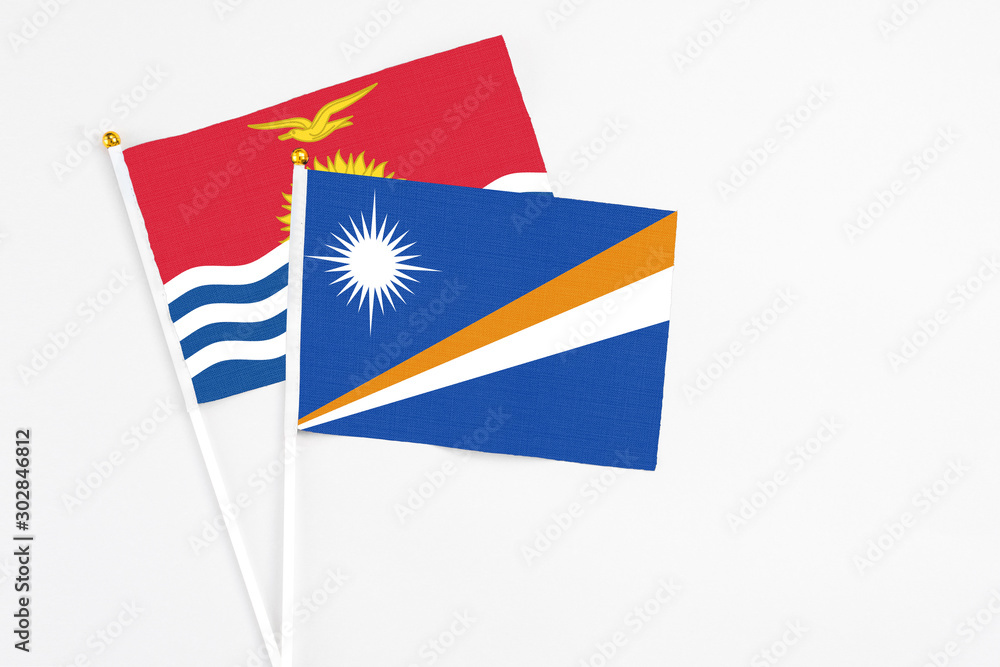 Marshall Islands and Kiribati stick flags on white background. High quality fabric, miniature national flag. Peaceful global concept.White floor for copy space. Marshall Islands and Kiribati stick flags on white background. High quality fabric, miniature national flag. Peaceful global concept.White floor for copy space.