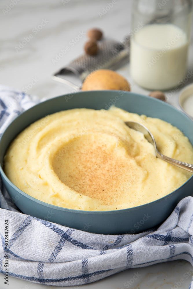 Schale Schüssel mit Kartoffelpüree mit Zutaten aus Kartoffeln, Milch, Salz, Butter, Muskatnuss dazu Küchentuch und Muskatreibe auf hell Marmor Hintergrund Schale Schüssel mit Kartoffelpüree mit Zutaten aus Kartoffeln, Milch, Salz, Butter, Muskatnuss dazu Küchentuch und Muskatreibe auf hell Marmor Hintergrund