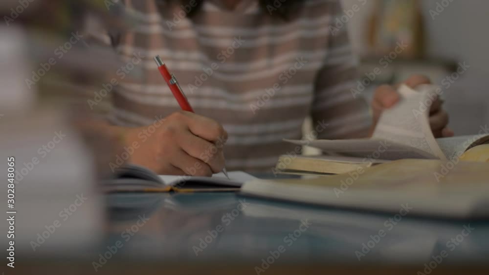 Girl is writing and reading during doing homework on the desk at home. Education concept. Panning shot. Girl is writing and reading during doing homework on the desk at home. Education concept. Panning shot.