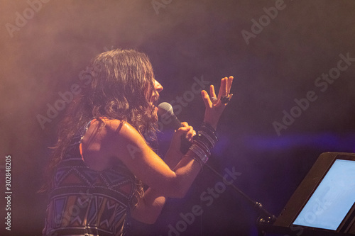 Fotografía a female musician is viewed from the side as she sings, with open mouth in micro