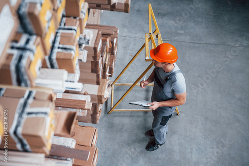Картината върху платно Top view of male worker in warehouse with notepad in hands