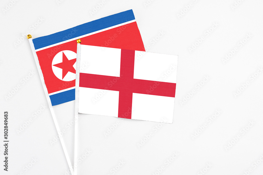 England and North Korea stick flags on white background. High quality fabric, miniature national flag. Peaceful global concept.White floor for copy space.