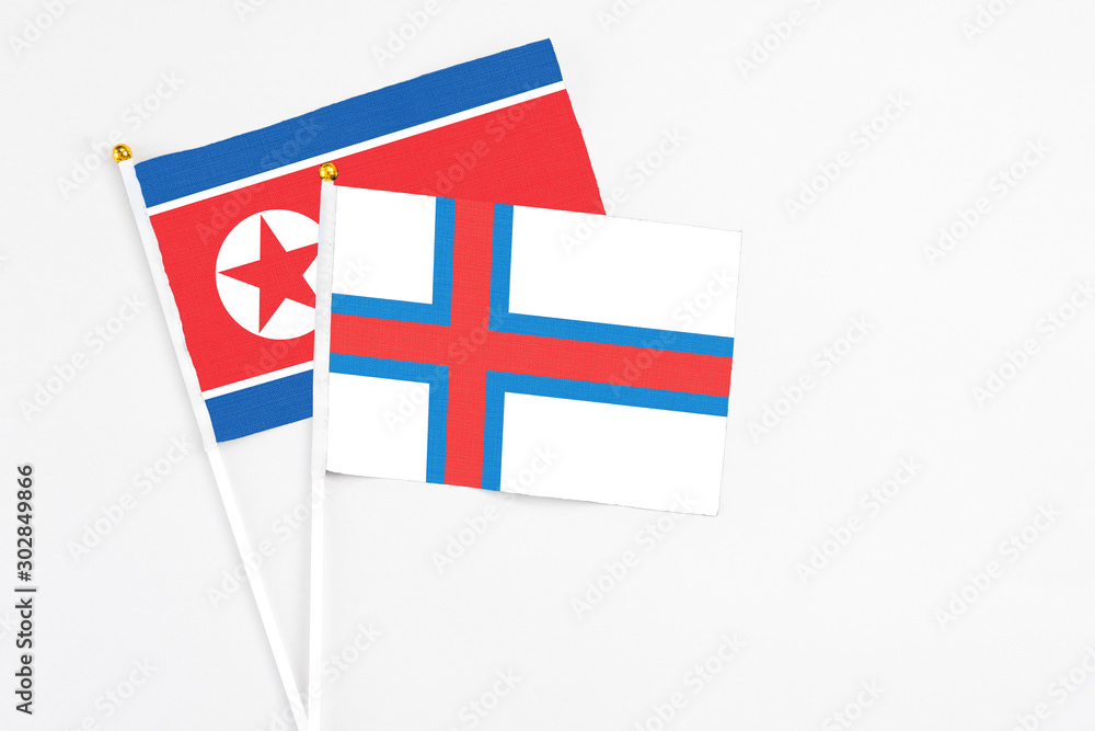 Faroe Islands and North Korea stick flags on white background. High quality fabric, miniature national flag. Peaceful global concept.White floor for copy space.