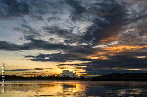 The tranquil waters of Lake Kununurra in the Kimberley region of Western Australia at sunset with tropical thunderstorms in the distance.