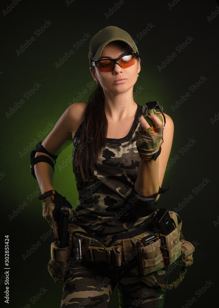 the girl in military overalls airsoft posing with a gun in his hands on a dark background the girl in military overalls airsoft posing with a gun in his hands on a dark background