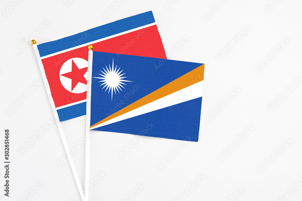 Marshall Islands and North Korea stick flags on white background. High quality fabric, miniature national flag. Peaceful global concept.White floor for copy space. Marshall Islands and North Korea stick flags on white background. High quality fabric, miniature national flag. Peaceful global concept.White floor for copy space.