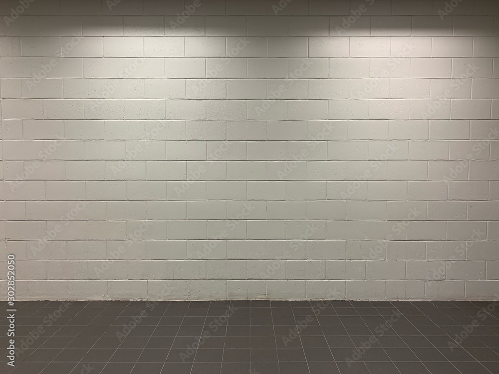 white brick block walls and black tile floors with light from above the ceiling white brick block walls and black tile floors with light from above the ceiling