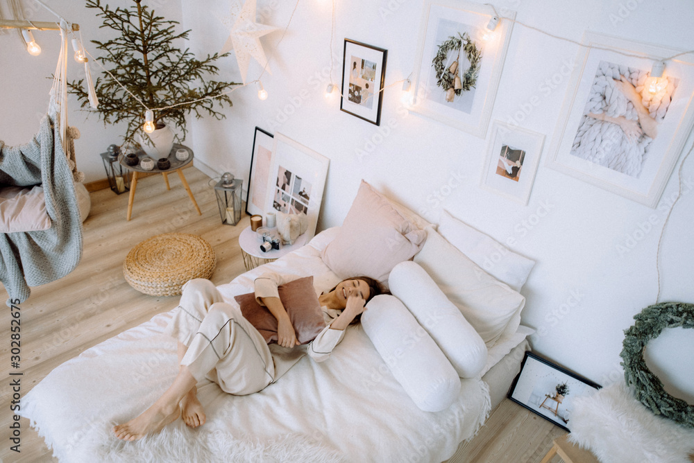 Young beautiful girl with white shirt on the bed. Lifestyle young women curly hair attractive awake relaxing on morning. - obrazy, fototapety, plakaty 