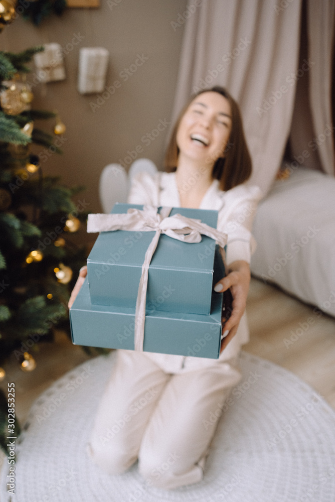 christmas, x-mas, winter, happiness concept - smiling woman with many gift boxes. Girl opens a gift against the background of the Christmas tree. happy young woman celebrating Christmas christmas, x-mas, winter, happiness concept - smiling woman with many gift boxes. Girl opens a gift against the background of the Christmas tree. happy young woman celebrating Christmas