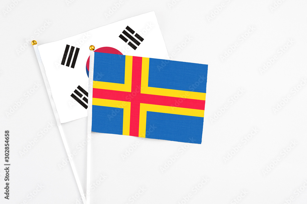Aland Islands and South Korea stick flags on white background. High quality fabric, miniature national flag. Peaceful global concept.White floor for copy space.