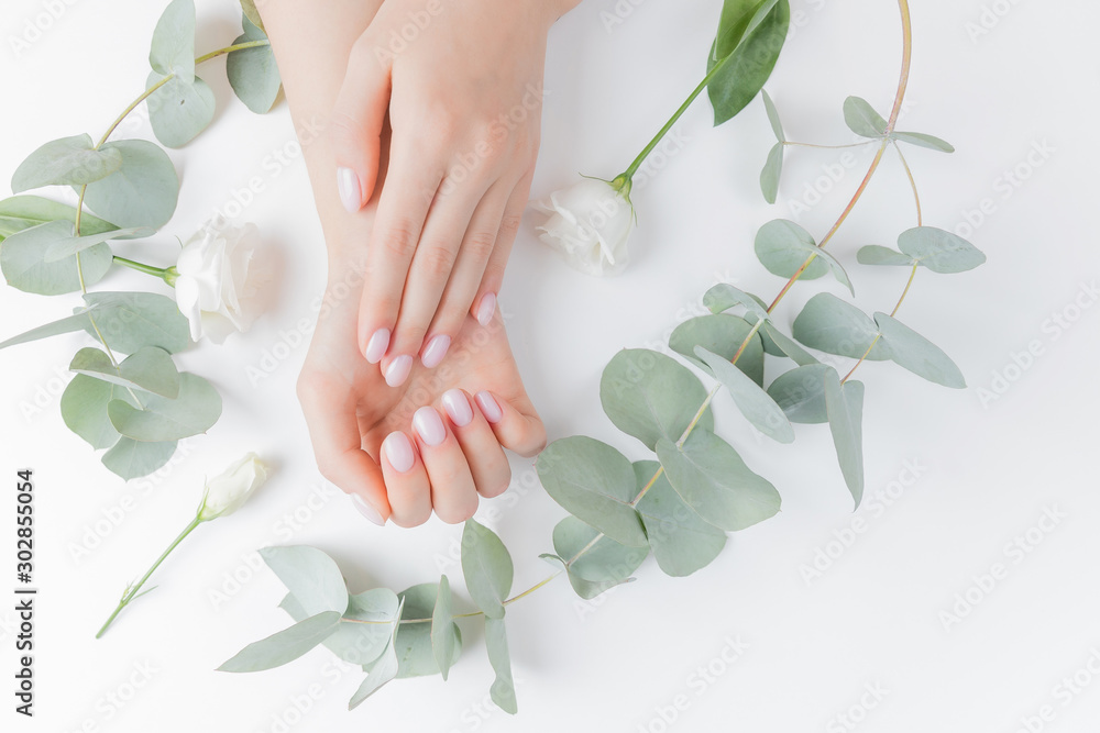 Stylish plain female hand manicure gel polish on white flower background eucalyptus, top view. Concept natural organic skin care - obrazy, fototapety, plakaty 