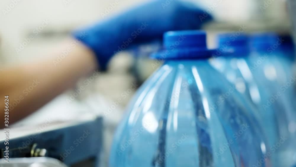 Woman is inserting corks in equipment covering plastic bottles with